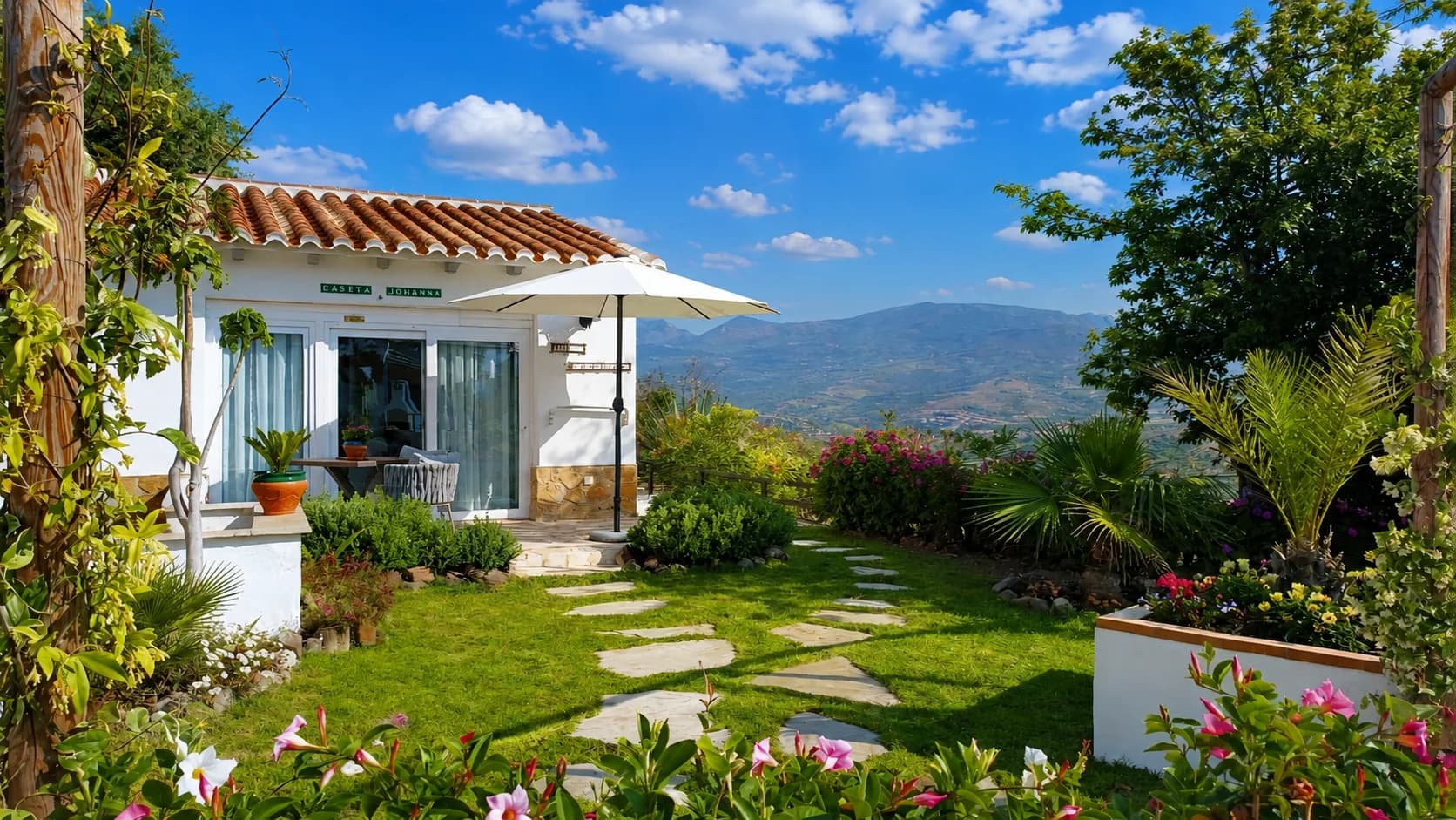 Charmantes Ferienhaus mit schönem Garten und Bergblick unter strahlend blauem Himmel.